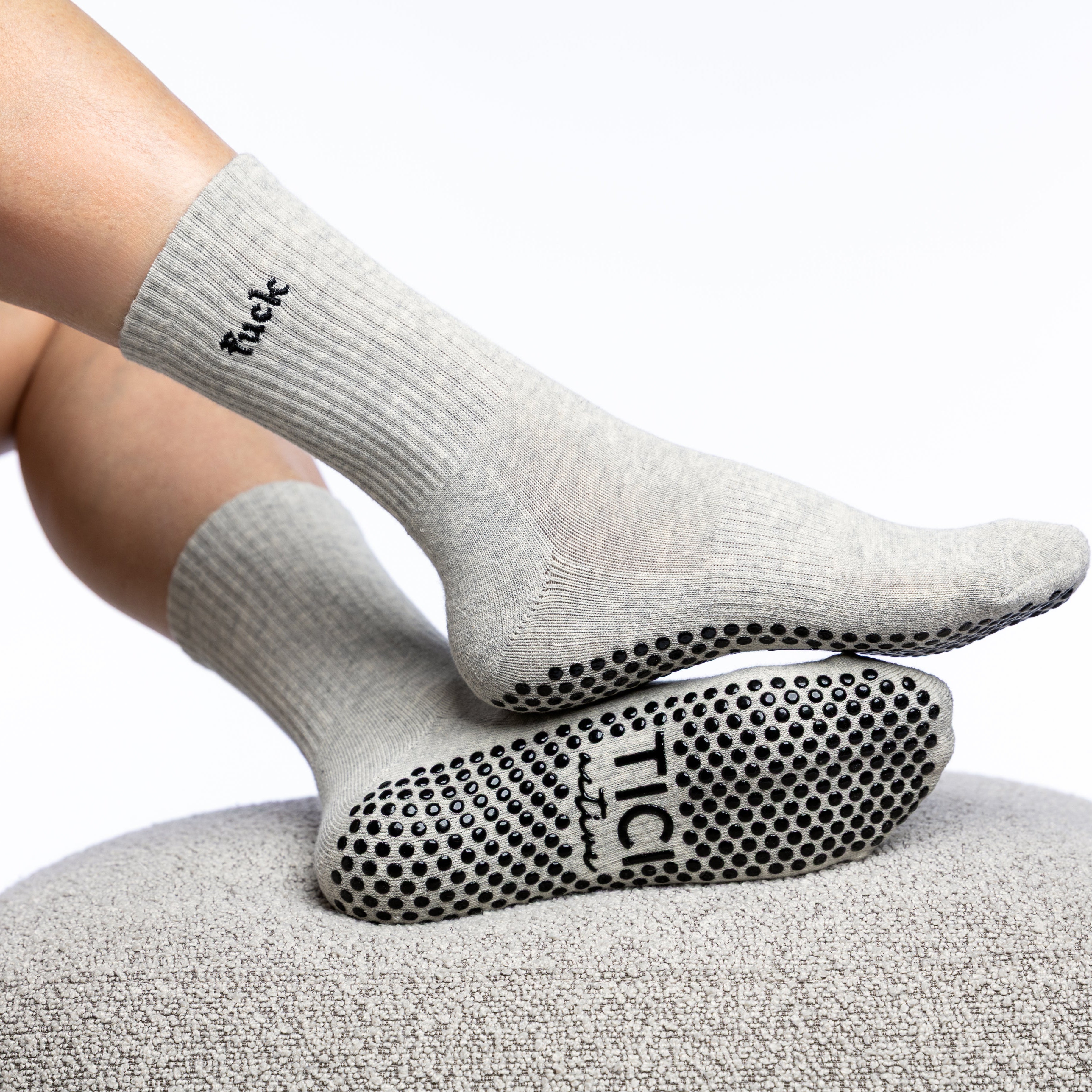 Person wearing gray grip socks with grip sole on a white background