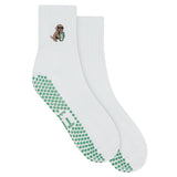 white grip sock by TICI ACTIVE with green grips. Embroidery is a golden retriever dog holding an iced matcha. 