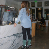 Person standing in a modern indoor coffee shop calabasas coffee house. matcha slouch grip socks from tici active.