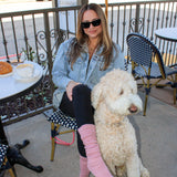 Woman with a dog on a patio with chairs and a table in the background wearing rose color tici active slouchy grip socks. Calabasas coffee house. 