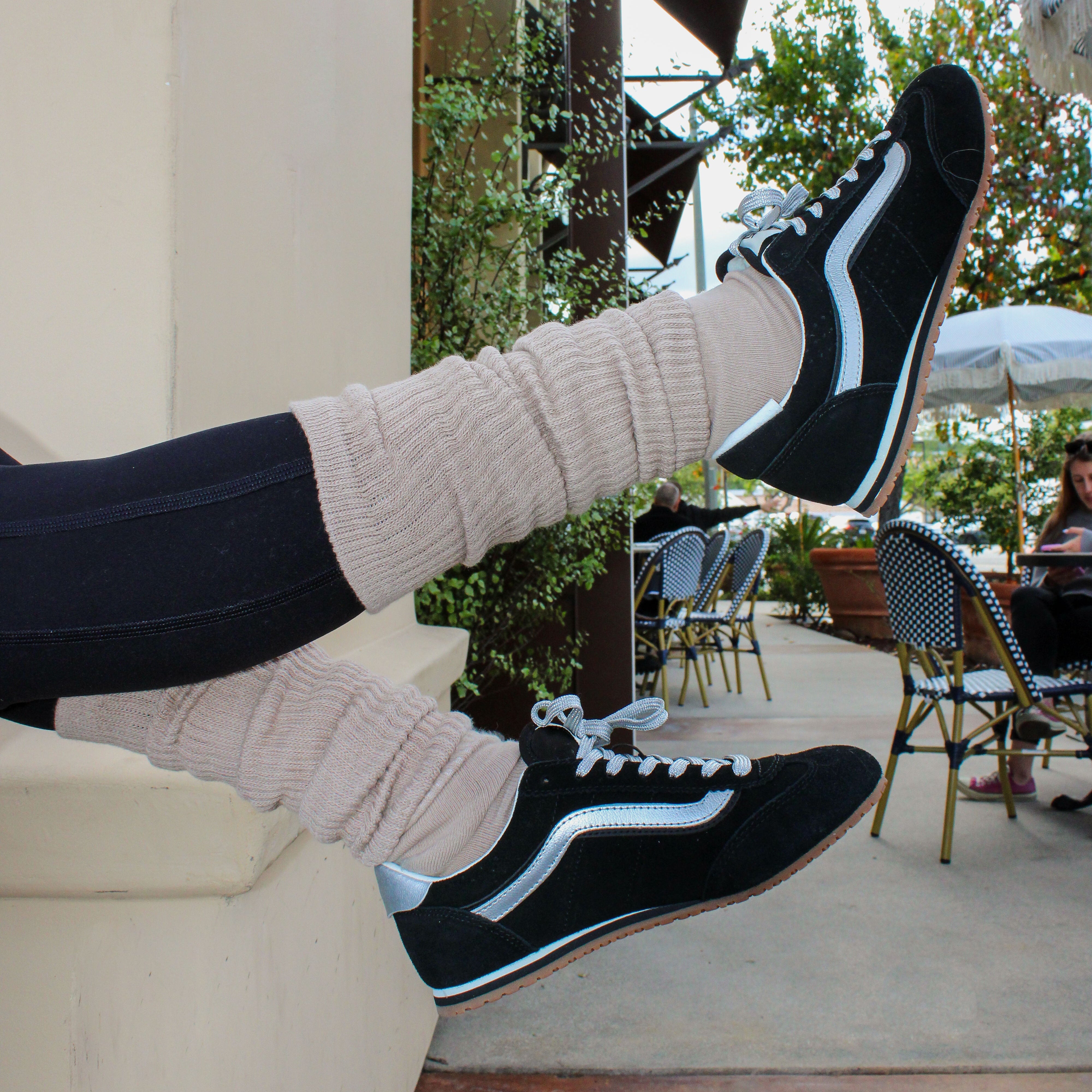 Person wearing black sneakers with white accents on a blurred outdoor background. person wearing latte colored crunchy grip socks for tici active.
