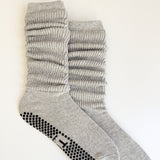 A pair of light gray ribbed crew socks with black grip dots on the sole, displayed on a clean white background.