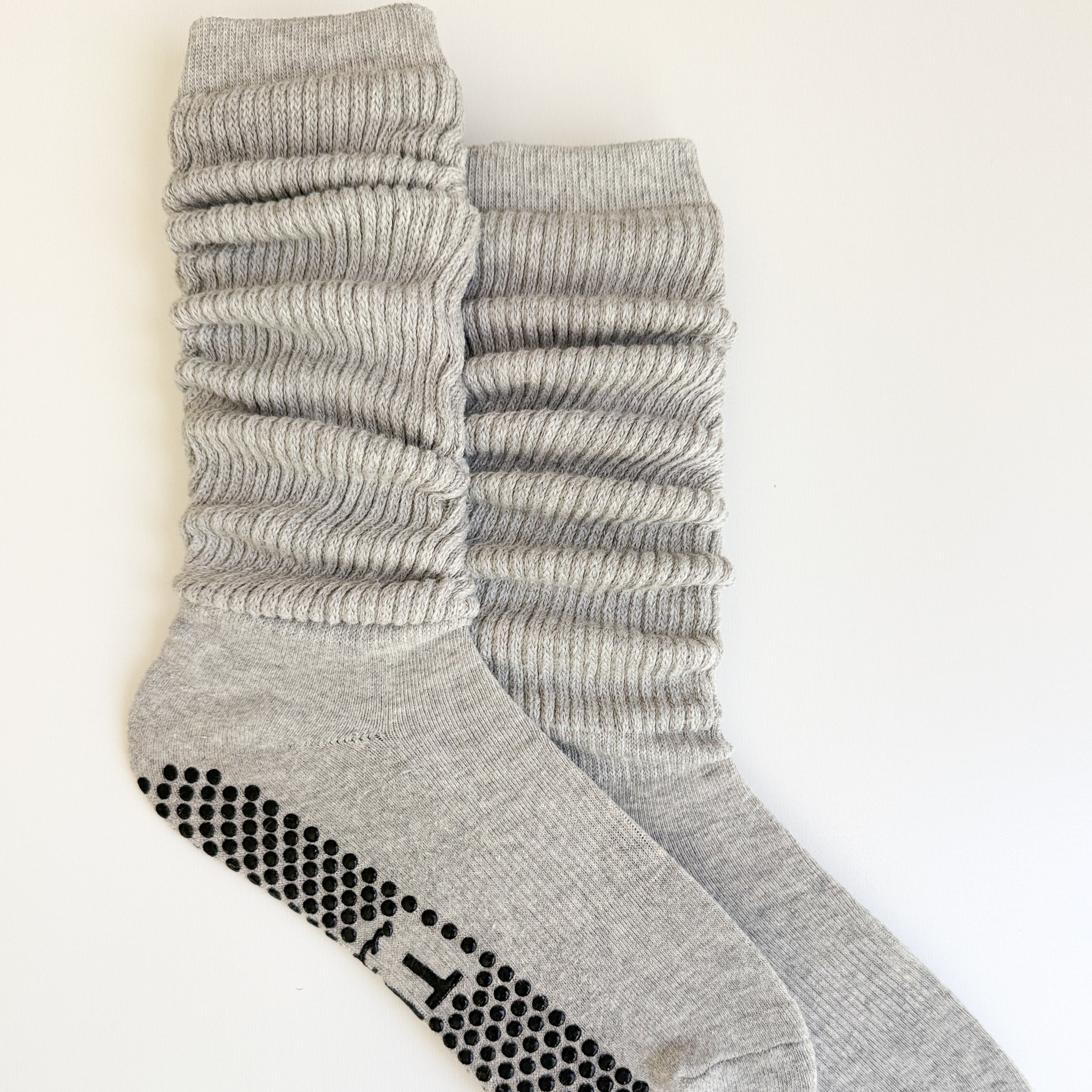 A pair of light gray ribbed crew socks with black grip dots on the sole, displayed on a clean white background.