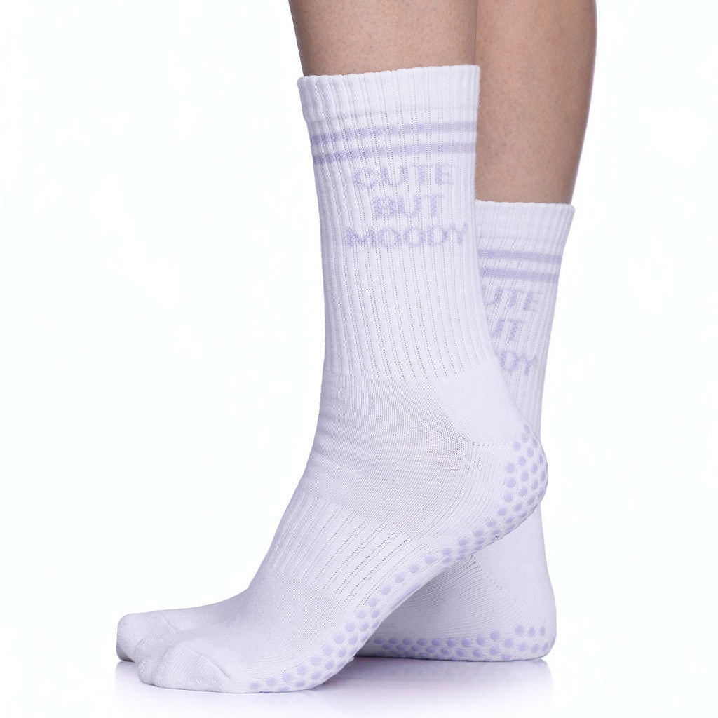 White pilates socks with lavender grips and text that read, "CUTE BUT MOODY"