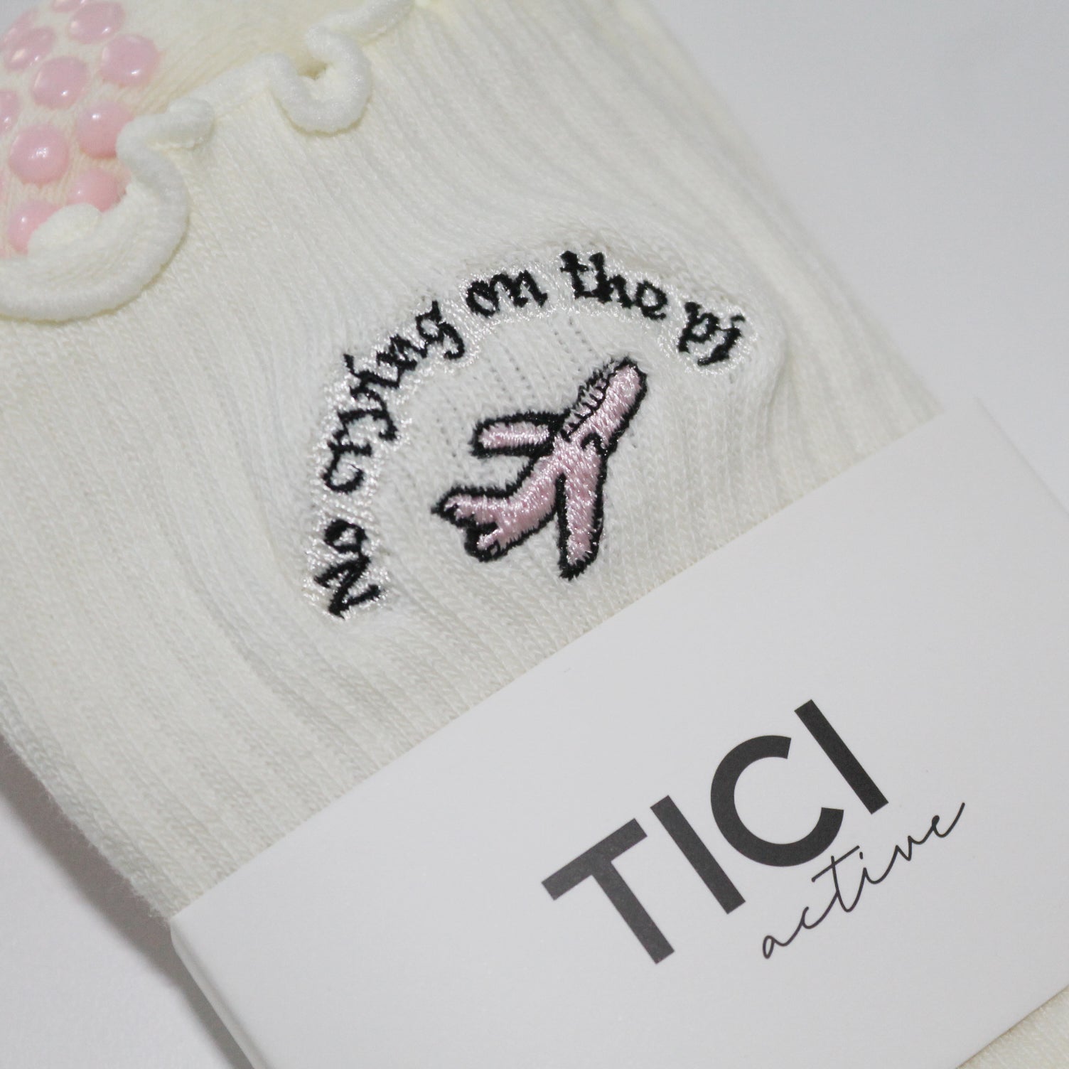 White socks with embroidered design and 'TICI active' label on a white background. pink private jet with text that reads, no crying on the PJ