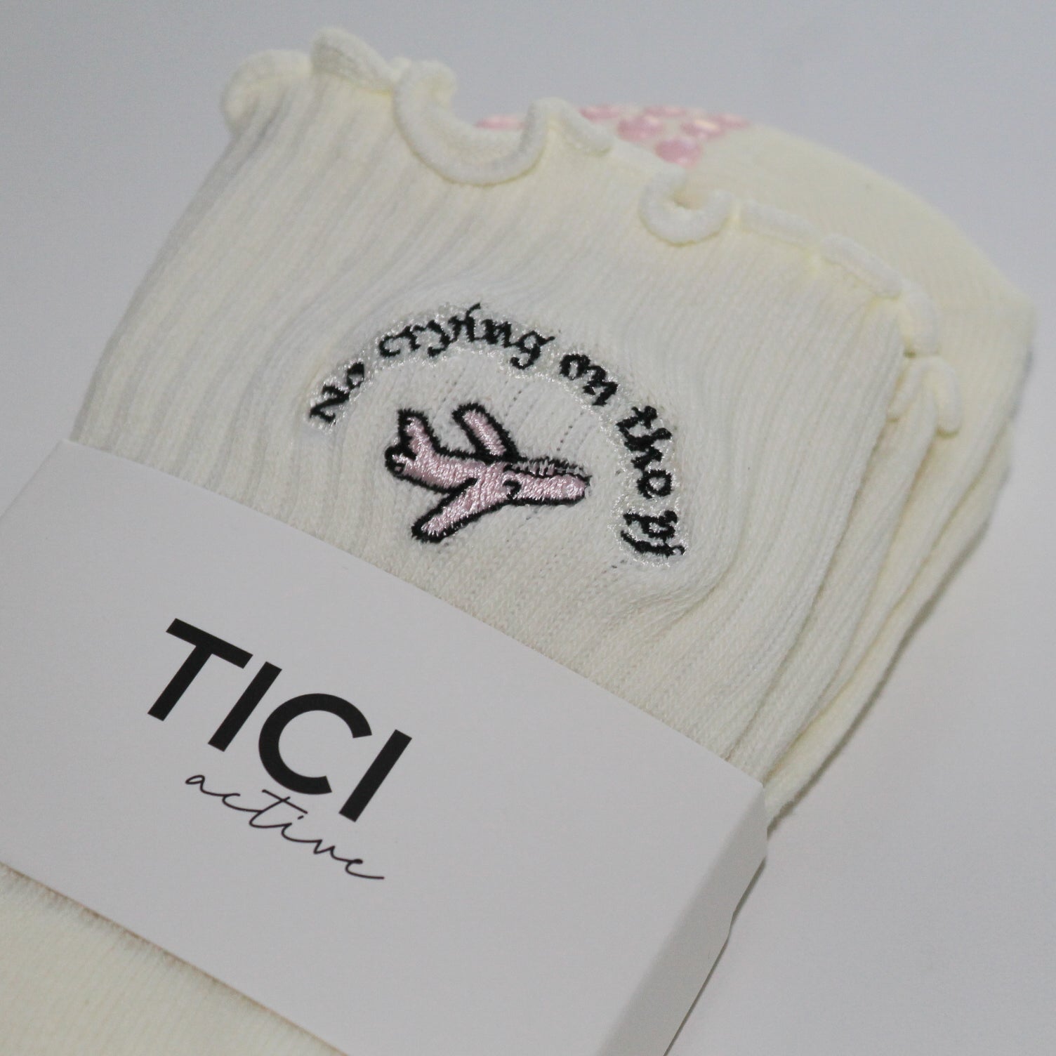 White socks with embroidered design and 'TICI active' label on a white background. pink private jet with text that reads, no crying on the PJ