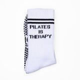 White pilates sock with black grips with 'Pilates is Therapy' text on a white background