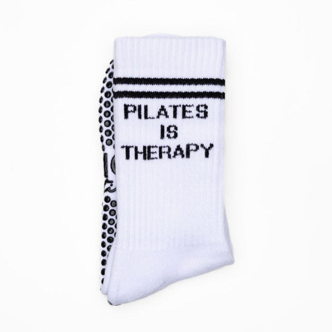White pilates sock with black grips with 'Pilates is Therapy' text on a white background