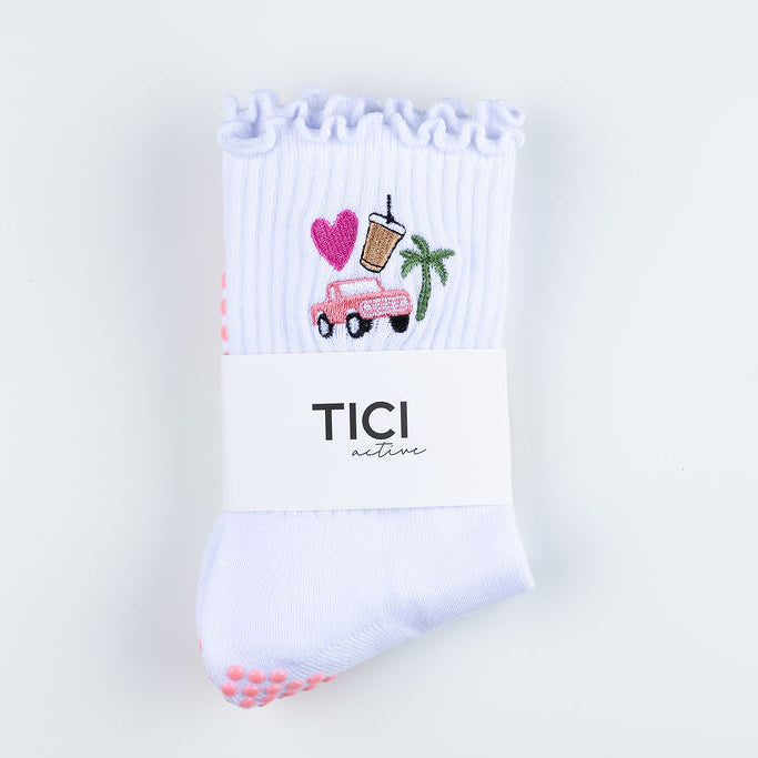 White TICI ACTIVE grip socks on a white background. Socks has pink grips. Embroidery is a vintage bronco truck, palm tree, heart and iced coffee. 