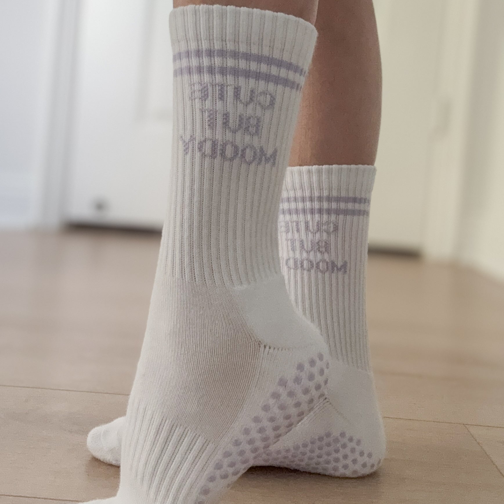 White pilates grip socks with lavender grips. text that reads, CUTE BUT MOODY.