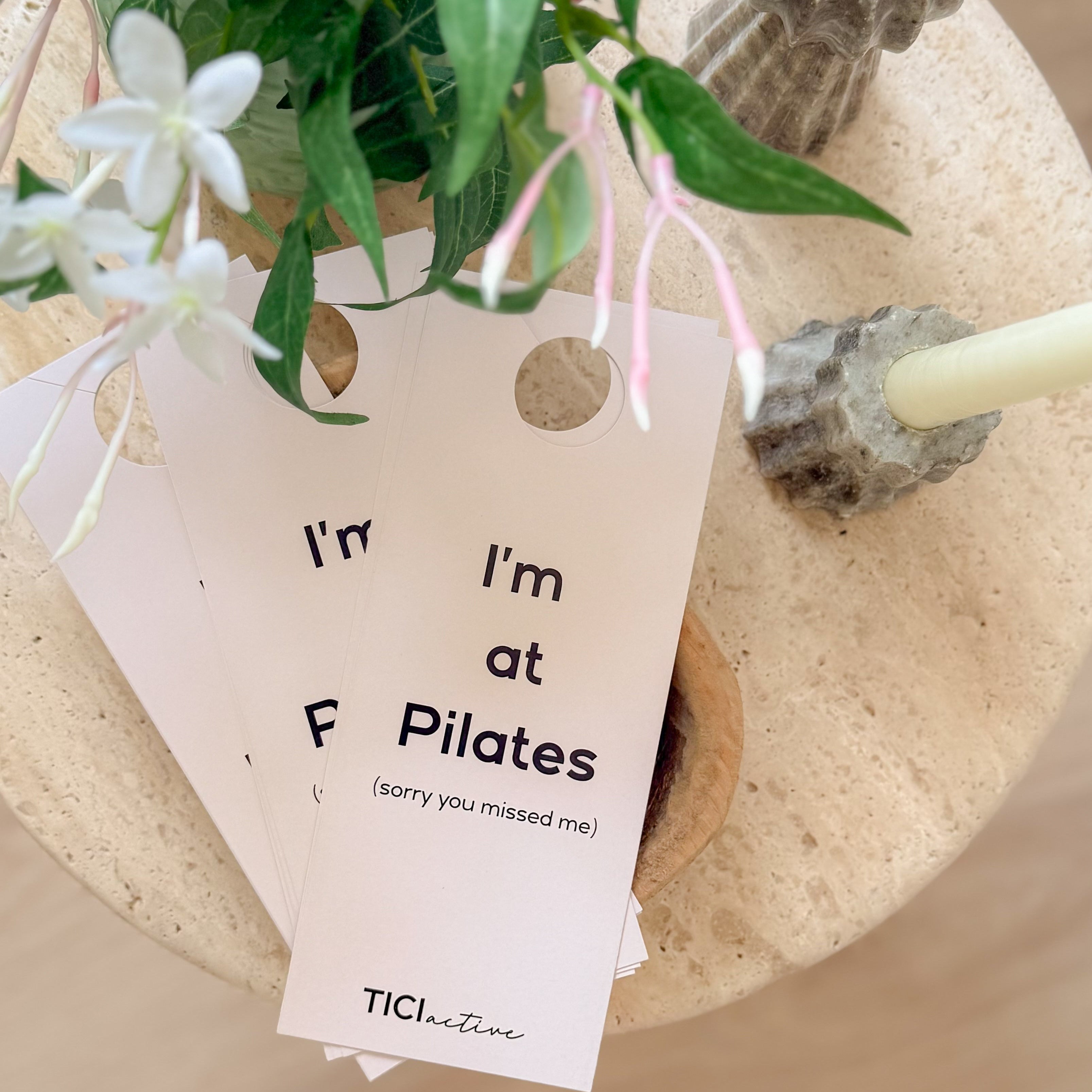 Potted plant with a tag reading 'I'm at Pilates' on a wooden surface