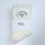 Pair of grip socks with a TICI active label on a light pair of cream socks and a pink jet. no crying on the pj in black embroidery text.

