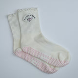 Pair of grip socks with a TICI active label on a light pair of cream socks and a pink jet. no crying on the pj in black embroidery text.