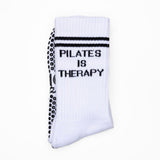White pilates sock with 'Pilates is Therapy' text on a white background