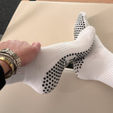 Person wearing white pilates sock with black grips on a pilates reformer
