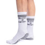 White socks with 'Pilates is Therapy' text worn by a person on a white background