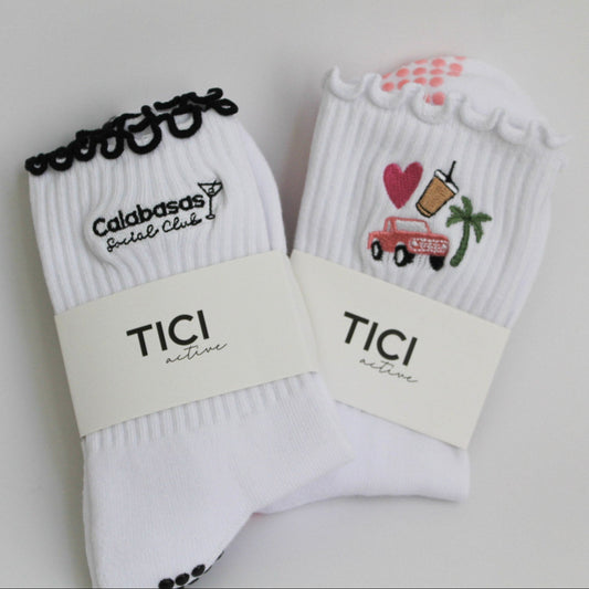 Two pairs of white socks with decorative elements and 'TICI' branding on a light gray background. tici active west coast duo