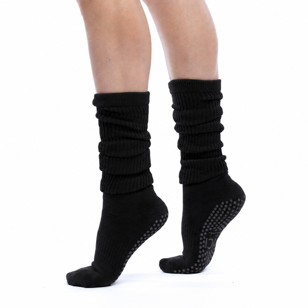 A pair of black ribbed knit grip socks worn on a person's feet, shown against a plain white background.